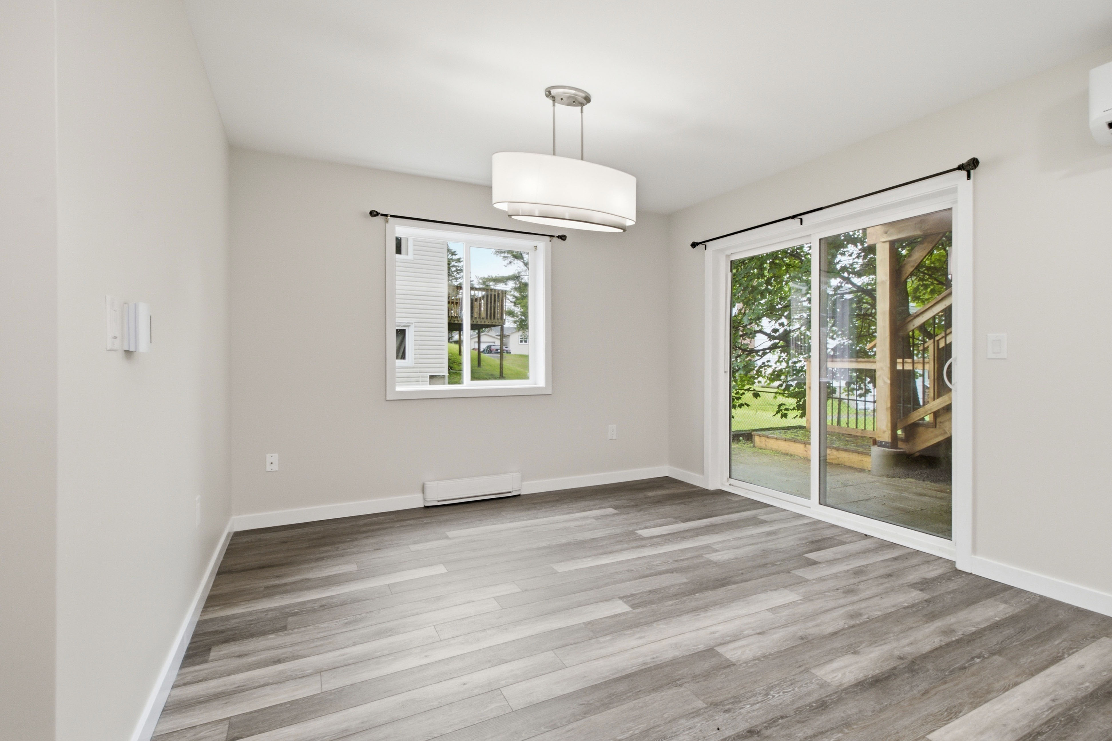 Dining area with a drum pendant light and a sliding glass door opening onto a private wood deck