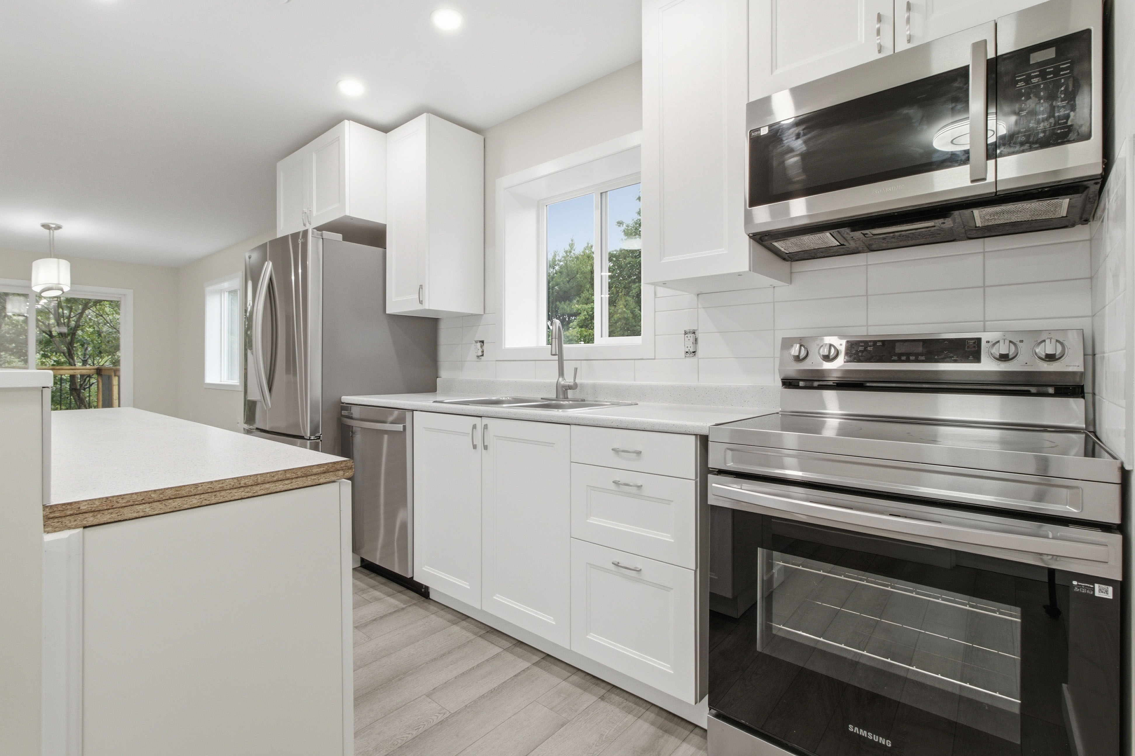 Kitchen with full Samsung stainless appliances, white shaker cabinets, and a window over the sink