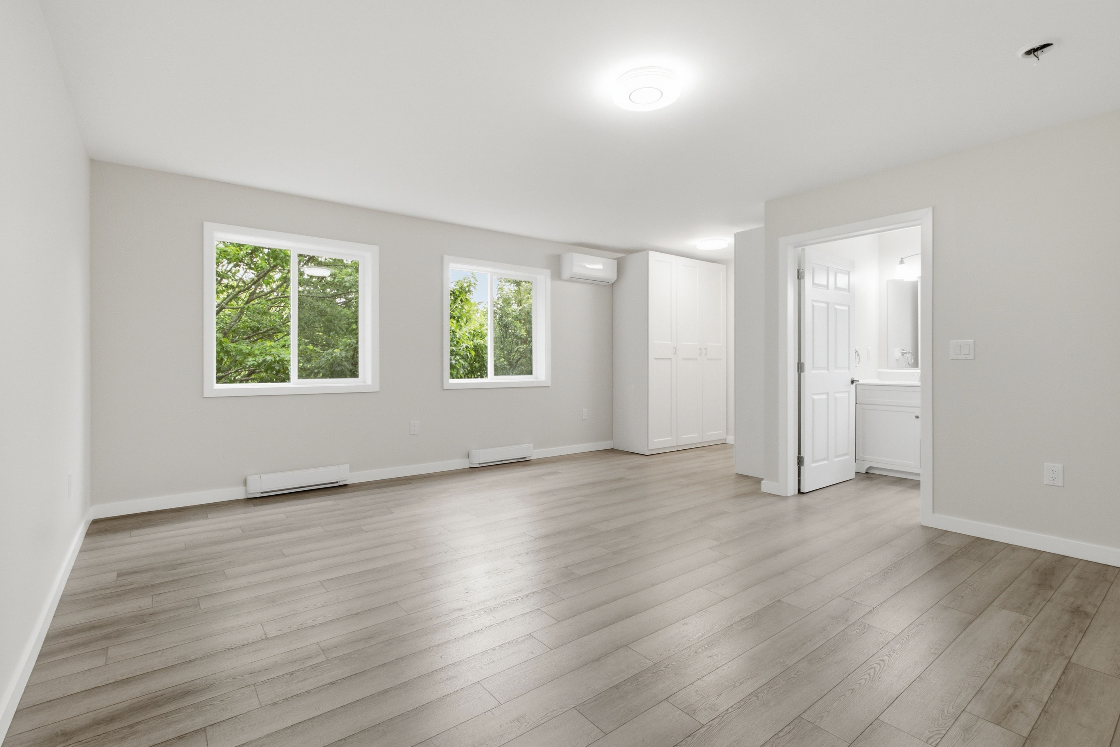 Primary bedroom with a built-in wardrobe, an ensuite bath, and twin tree-facing windows