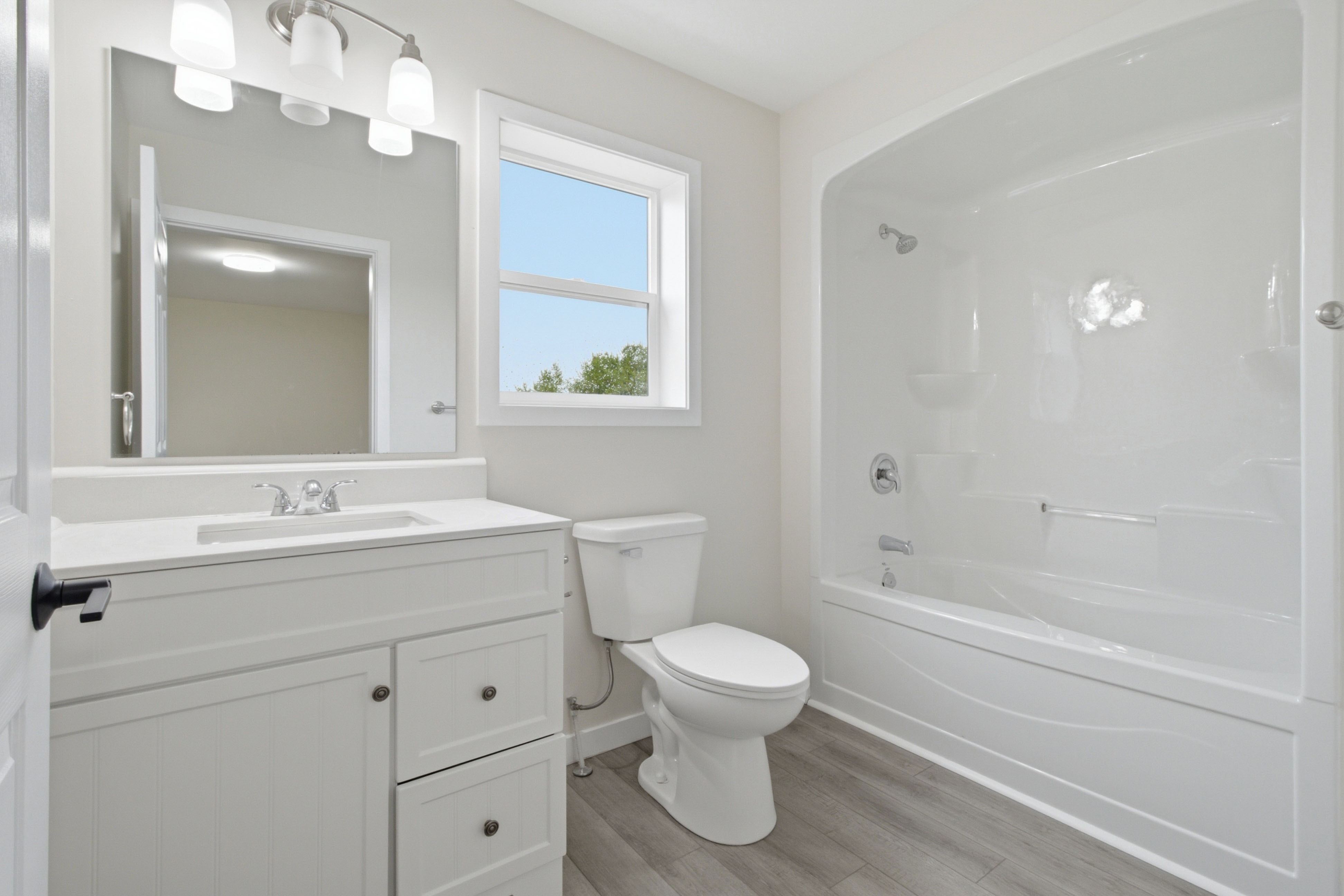 Full bathroom with a tub-and-shower surround, a white shaker vanity, and a mirror